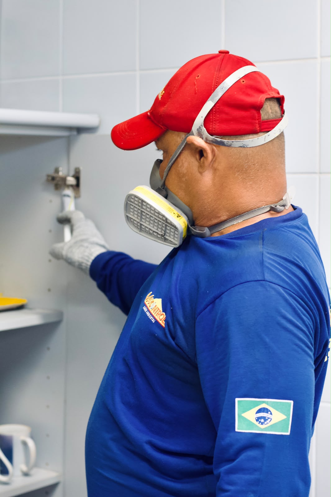 Técnico da MaxControle tratando armários contra pragas em cozinha
